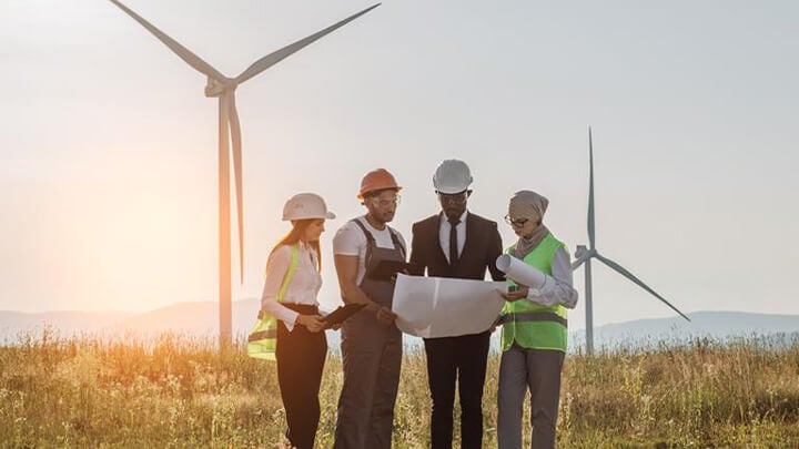 People in high visibility gear in front of wind turbines