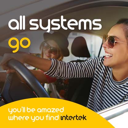 A woman driving a car with her friend, both smiling broadly